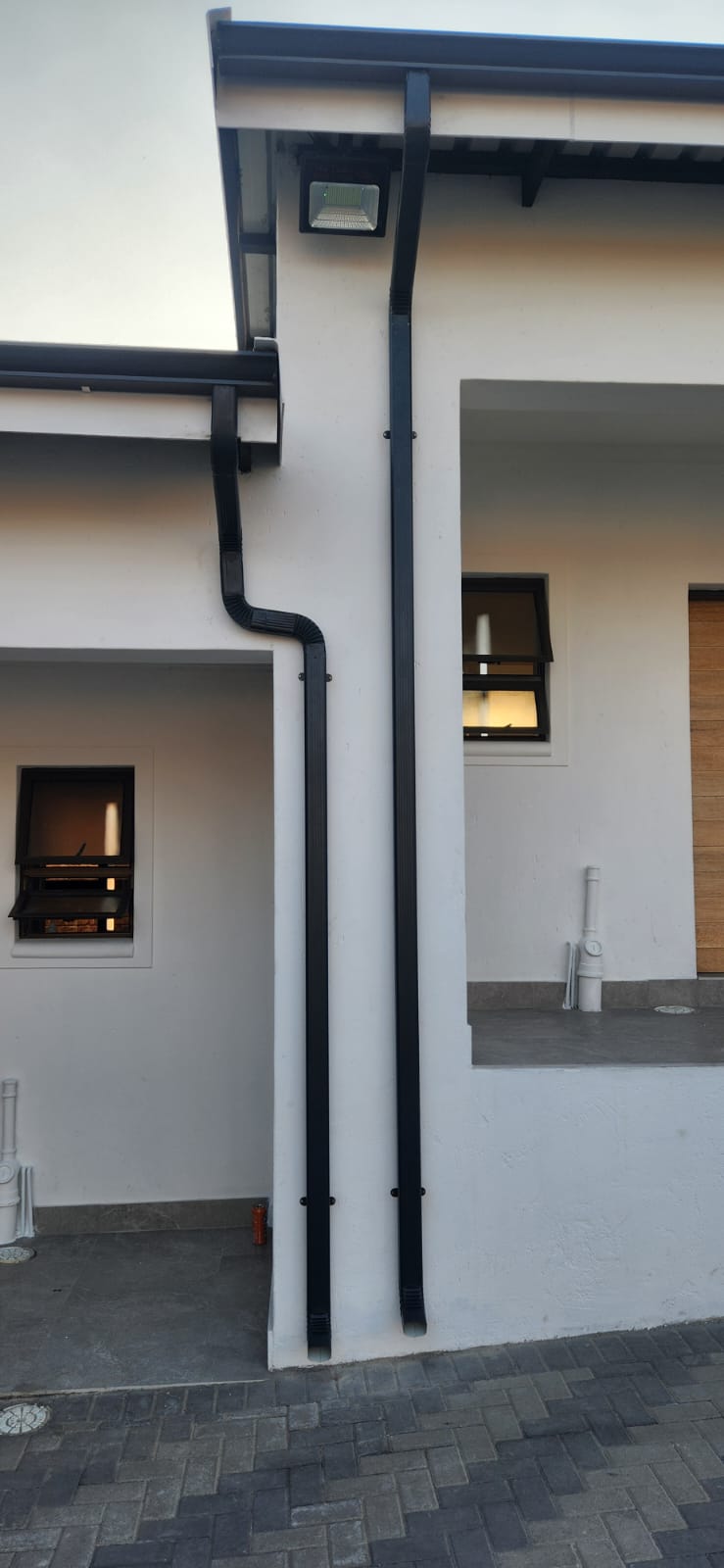 Close view of completed charcoal downpipes installed on a white exterior wall
